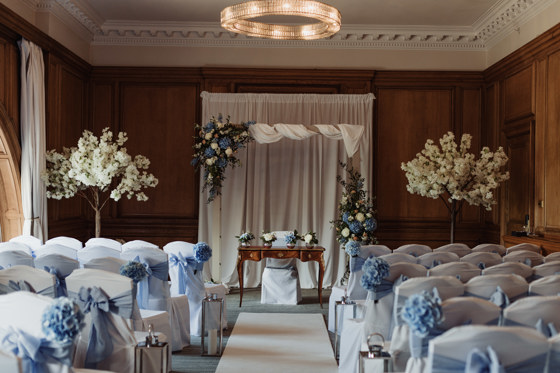 Image of blue and white themed decor for wedding ceremony, with floral decorated square arch
